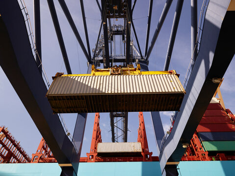Crane unloading cargo container from ship