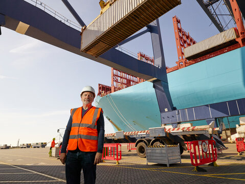 Dock worker by cargo container and truck at Port of Felixstowe, England