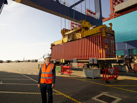 Dock worker by cargo container and truck at Port of Felixstowe, England
