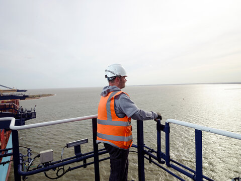 Dock worker looking at view from crane railing