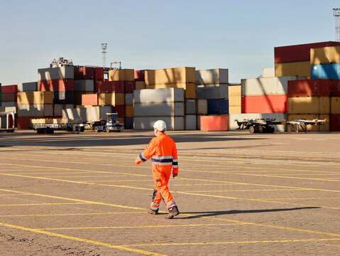 Dock worker walking towards shipping containers in dock, Felixstowe, England.