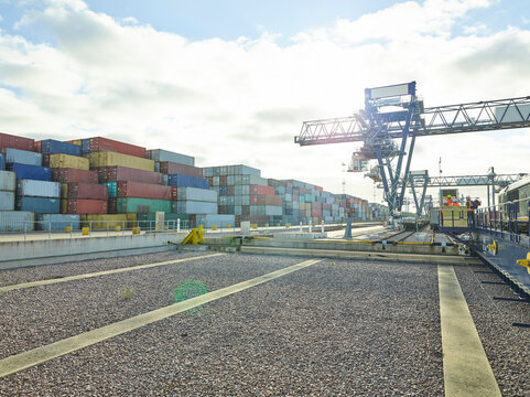 Cargo cranes and shipping containers at dockyard railway, Felixstowe, England.