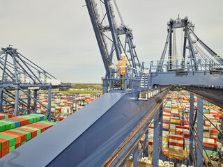 Dock worker on cargo crane platform looking away, elevated view, Felixstowe, England