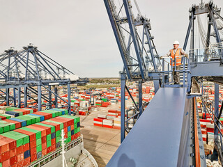 Dock worker looking across dockyard with shipping containers, elevated view from cargo crane, Felixstowe, England