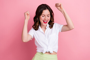 Photo of lucky excited young lady wear white shirt screaming rising fists isolated pink color...