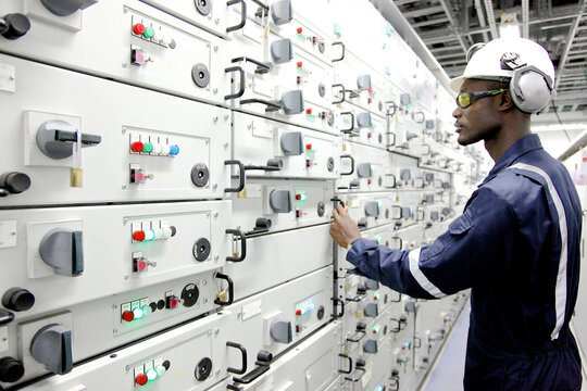 Worker in hardhat at control panel