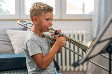 Side view of a boy playing a trombone.