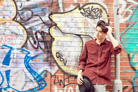 Teenage boy leaning against brick wall