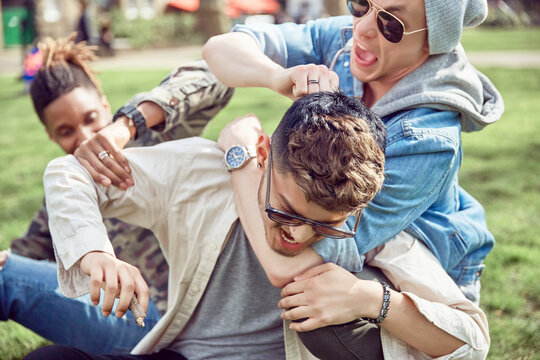Teenage boys play fighting in park