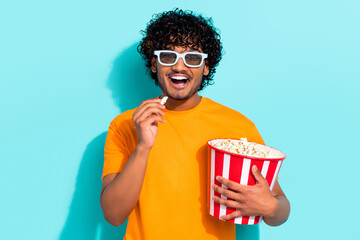 Photo of funny young indian man eating bucket tasty pop corn chips enjoy new film cinema...