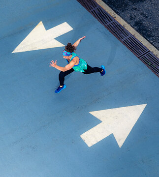 Young woman running on road with arrow road marking