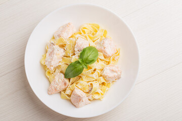 Top view on a plate of Fettuccine pasta with salmon in creamy sauce on wooden table. Mediterranean cuisine.