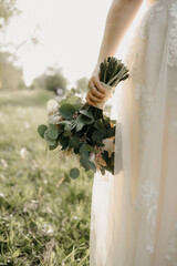 bride holding a bouquet of flowers with grass and land behind