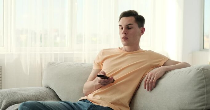 Caucasian man enjoying his favorite shows, seated on the cozy couch, he immerses himself in captivating stories, gripping dramas, or hilarious comedies playing on the television screen before him.