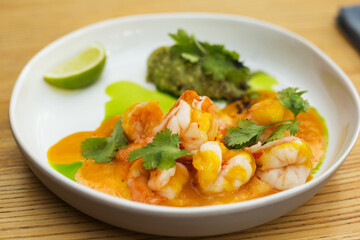 Grilled tiger prawns served with guacamole combined with hollandaise sauce, mango sauce and sweet chili. Garnished with cilantro. Healthy eating.