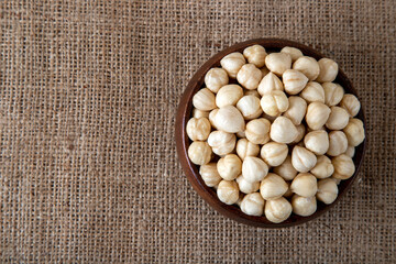 Top view of a bowl full of peeled hazelnuts  on burlap sack,copy space