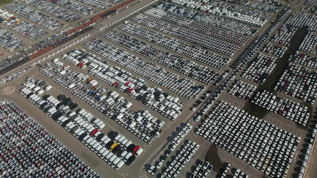 Aerial view of manufactured new cars parked in a factory parking lot ready to be delivered to a customer.