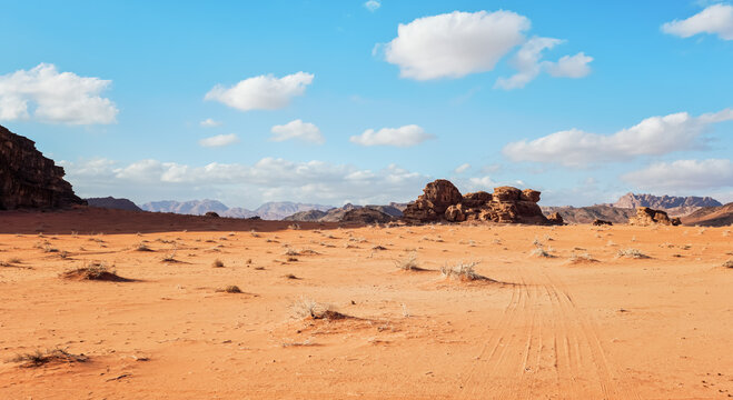 Orange Red Sand Desert, Rocky Formations And Mountains Background, Blue Sky Above - Typical Scenery In Wadi Rum, Jordan