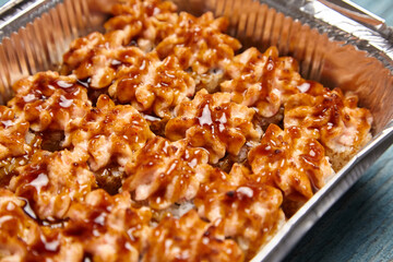 Baked sushi rolls in a baking dish on blue wooden background. Hot sushi rolls with different kind of fish and fillings