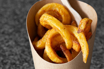 Curly fries takeaway in a cardboard carton with a wooden fork. Biodegradable plastic free eco friendly takeaway container