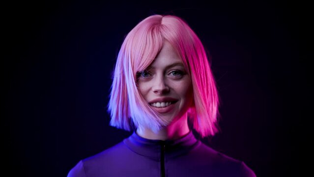 Beautiful woman in futuristic costume over dark background. Violet neon light. Girl smiling and looking at the camera.