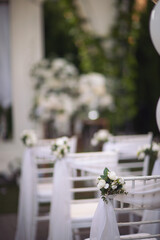 Ceremony in the bosom of nature. White chairs with flowers set in the grass. white chairs lined up for an event accompanied by a bouquet of white flowers.