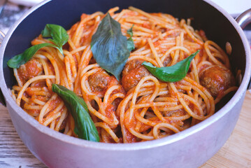 Spaghetti with meatballs, tomato sauce and basilic, popular italian pasta dish served in a pan.