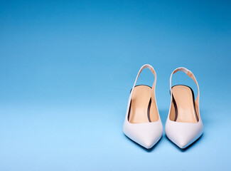 Fancy white open-back pumps with pastel insoles with black outlines. Isolated on a gradient blue background with copy space on left and on top. Concept for modern and fashionable shoe store.