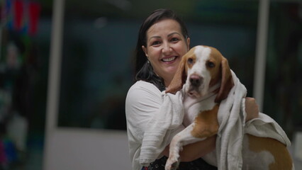 Female Pet Shop Employee covering Dog Beagle with towel after bath. Woman carries Canine Companion...