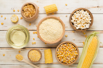 Maize products with fresh corn cobs on wooden background, top view