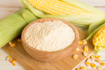 Corn flour with fresh cobs on wooden table