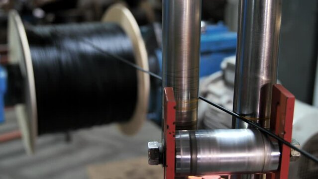 Winding of the optical cable to the bobbin in the production line. Cable pdroduction. Cable factory. Winding the black cable onto the reel. Production line at factory for production of Internet wire