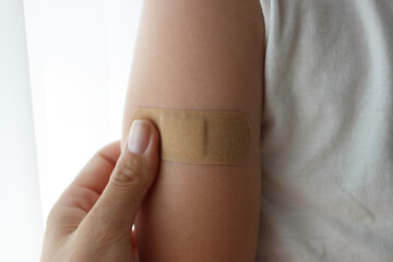 Arm with a plaster on the skin. Concept of vaccination and immunization, soft focus background