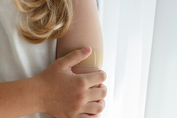 Arm with a plaster on the skin. Concept of vaccination and immunization, soft focus background