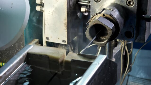 Close-up of an extruder that comes out of a fiber optic cable wrapped in black plastic. Covering the Internet wire with a rubber insulating layer. Cable production line at the factory.