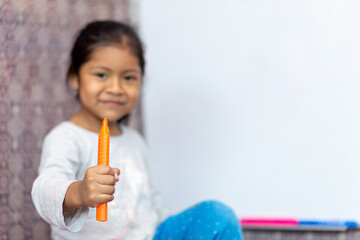 Niña latina sonriente y feliz, escribiendo en la pizarra de clases con plumones de colores. Espacio para texto.