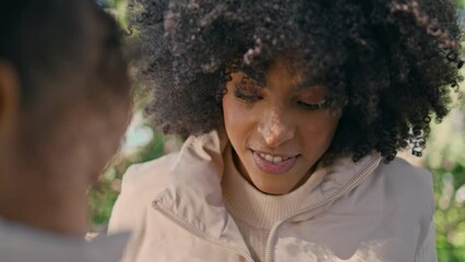 Smiling woman sitting with daughter in garden close up. African american family