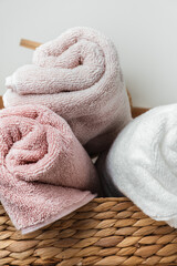 Close up of white and pink clean towels folded in a wicker basket