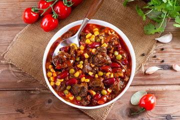 Goulash, beef stew or mexican dish chili con carne soup with meat, vegetables and spices on table. Rustic style. Top view.