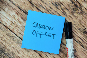 Concept of Carbon Offset write on sticky notes isolated on Wooden Table.