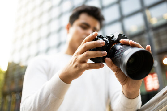 Low angle man viewing photos on camera against blurred background