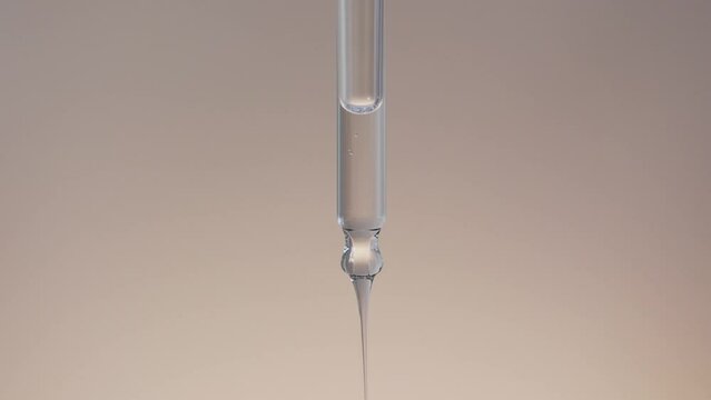 Macro of drop of hyaluronic serum is falling down from chemical dropper 