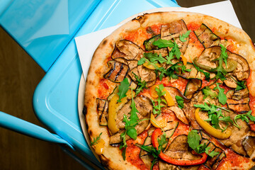 Delicious and colourful healthy pizza with vegetables served on wooden board on blue background