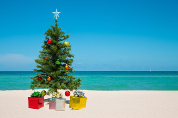 Christmas Tree on the beach. Merry Christmas. Present gift box. Happy New Year. Winter Holidays. Miami Florida vacation. Decorated Christmas pine or fir tree. Tropical Nature. Blue ocean on background