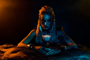 Photo of mysterious viking mythology wizard woman hold elixir cup yellow lights isolated on black...