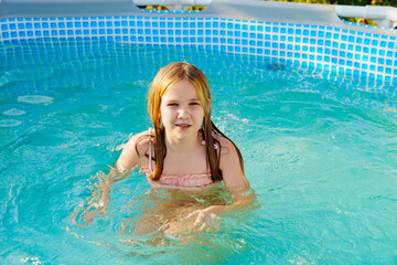 Naklejka premium Cute teenage girl in pink swimsuit playing in a small pool. 