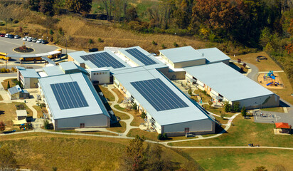 Aerial view of american school building with rooftop covered with photovoltaic solar panels for production of electric energy