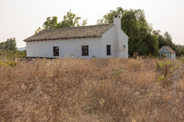 Antigua casa de campo entre arbustos secos, en peligro de incendio
