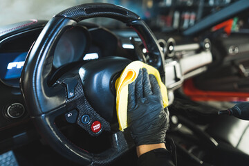 closeup shot of a specialist with gloves cleaning a steering wheel, car detailing. High quality photo