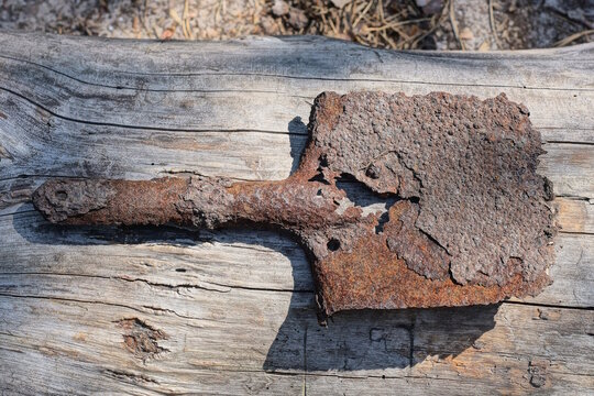 one old small brown rusty iron sapper shovel lies on a gray wooden table on the street